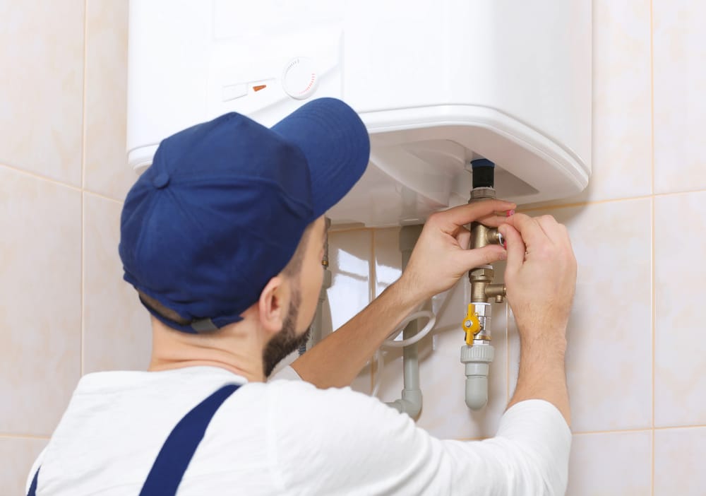 Image: A modern water heater with a plumber checking the unit.